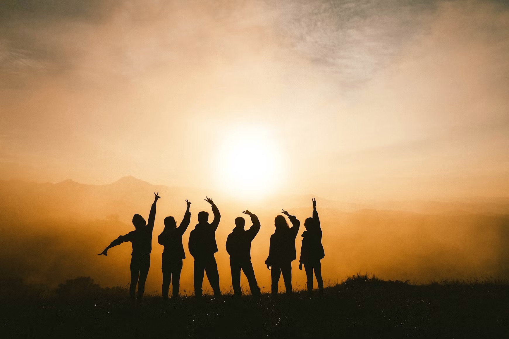 A group of people outdoors watching the sunset.